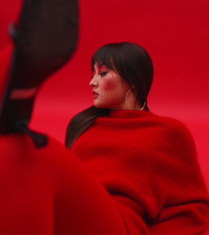 一个亚洲女孩模特穿着红色毛衣和连裤袜躺在红色背景的地板上。艺妓穿着红色的衣服