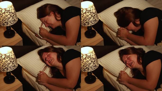 不开心的女人躺在床上，趴在卧室的枕头上歇斯底里地哭泣。晚上睡前歇斯底里，无法控制地抽泣。