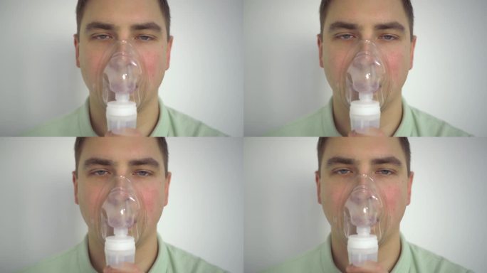 一个年轻人用吸入器呼吸。一名戴着氧气面罩的男子因呼吸道感染正在接受治疗。4 k