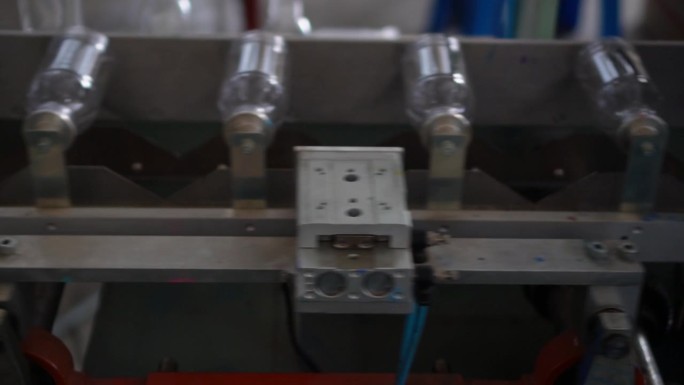 在泰国清迈的一家饮用水生产厂，塑料饮用水瓶上的传送带系统导致瓶子标签印刷的慢动作视频。