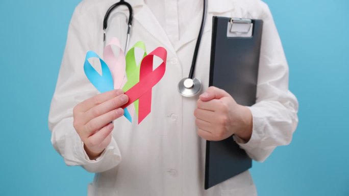 年轻女医生手持小彩带的特写，蓝色、红色、绿色、粉色表示支持人们的生活和疾病。健康，医疗，意识和保险概