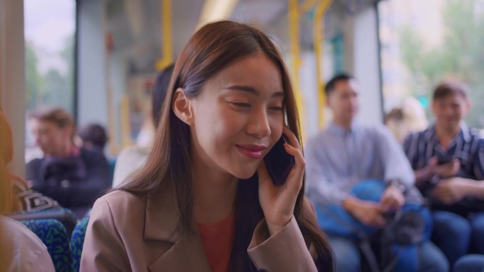 亚洲女旅客在火车上打电话。有魅力的女游客在智能手机上聊天，独自旅行，享受现代交通工具的假期旅行。