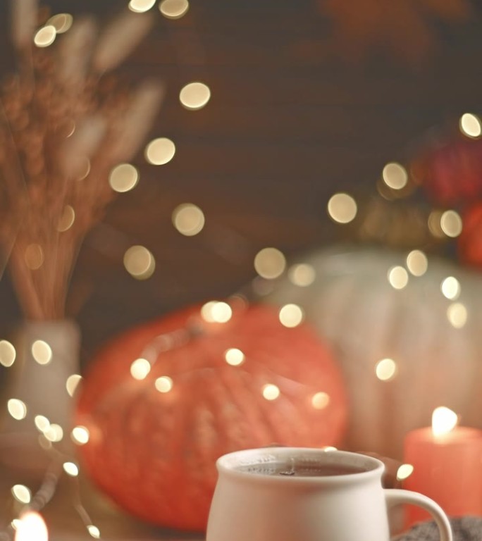 秋天惬意的构图。杯子里的茶，南瓜和蜡烛