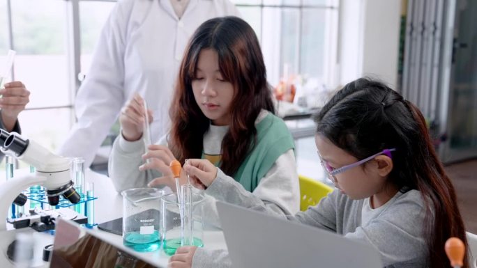 来学习科学学科的女学生来自不同的年代，做实验的女师长帮助教低年级的学生，后面有老师站在旁边，为了实验