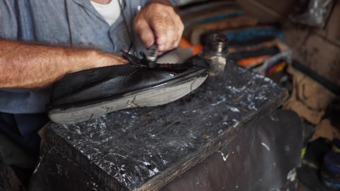 补鞋匠的手在补鞋，用针在缝