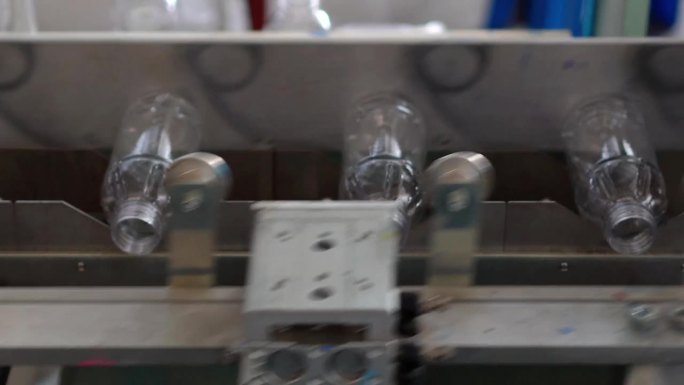 在泰国清迈的一家饮用水生产厂，塑料饮用水瓶在通向瓶子标签印刷过程的传送带系统中的视频片段。