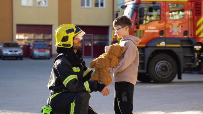 获救的小男孩和站在消防车旁的消防员的肖像。灭火行动中的消防员