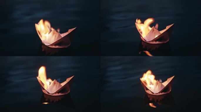 夜间漂浮在河上燃烧的折纸船的高角度特写