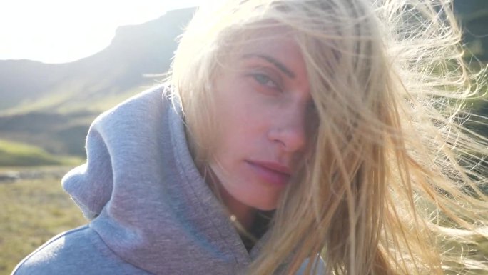 一个美丽的金发女人在阳光下的肖像，背景是冰岛南部令人难以置信的风景