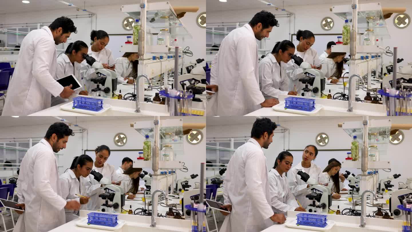 专注的生物系学生在实验室里分析样本，男老师帮助两名女学生