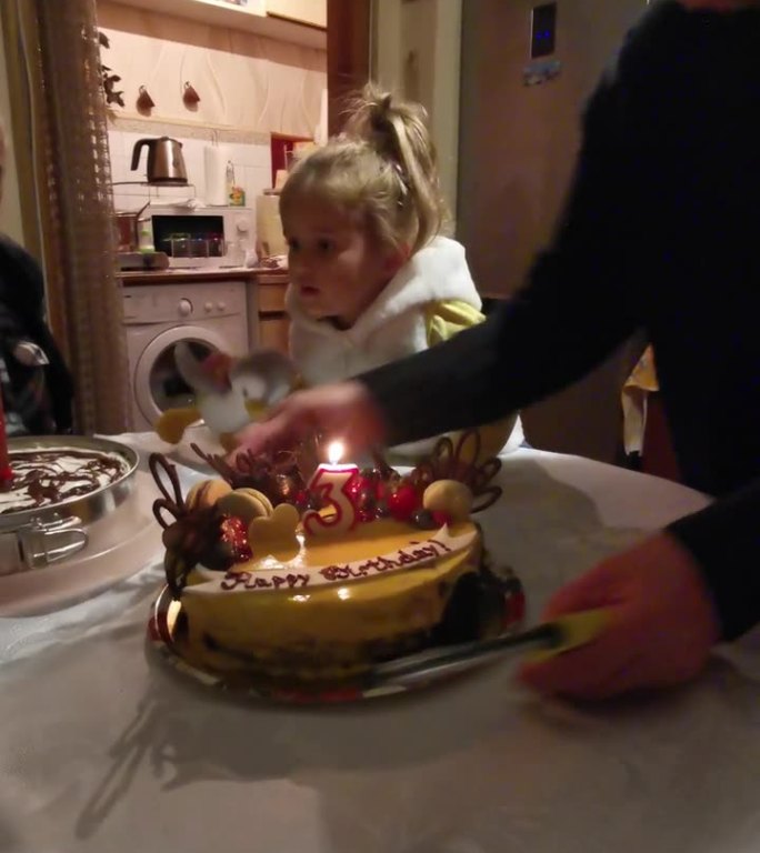 女孩在家里和家人一起庆祝三岁生日。