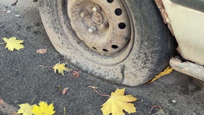 车胎瘪了，车体生锈，是一辆废弃的车