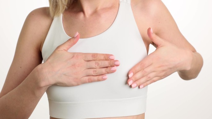 穿白色上衣的女人触摸乳房来检测痛点