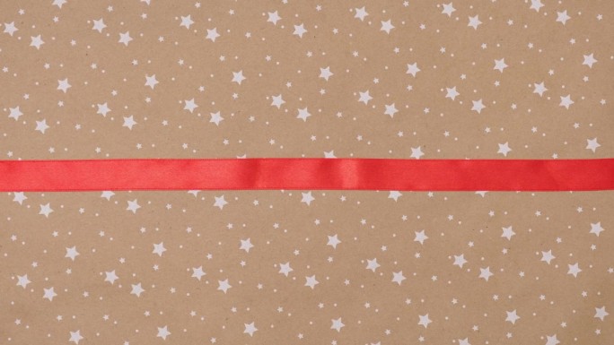 拆开礼物，用红色缎带和手工蝴蝶结系在星星背景的工艺纸上。揭示绿屏定格动画。