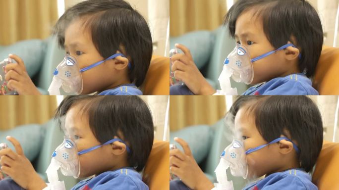 亚洲男孩在医院一边玩手机游戏一边使用吸入器。