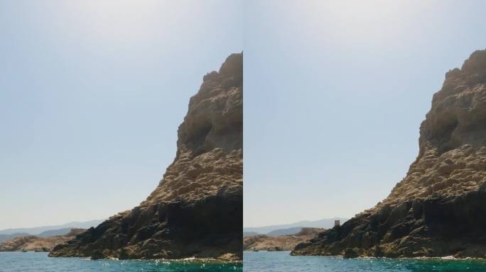 夏季，从法国鲁斯岛的一艘观光船上俯瞰山脉、岩石、海水和帆船的垂直照片。