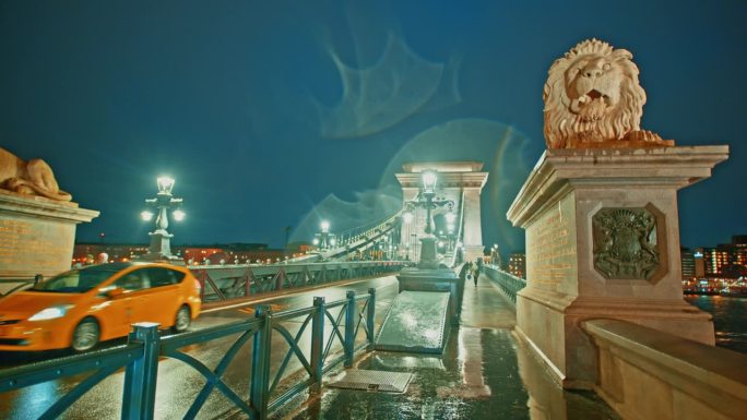 手持拍摄的汽车行驶在照亮sz<s:1> chenyi链桥黄昏在晴朗的蓝天在布达佩斯，匈牙利