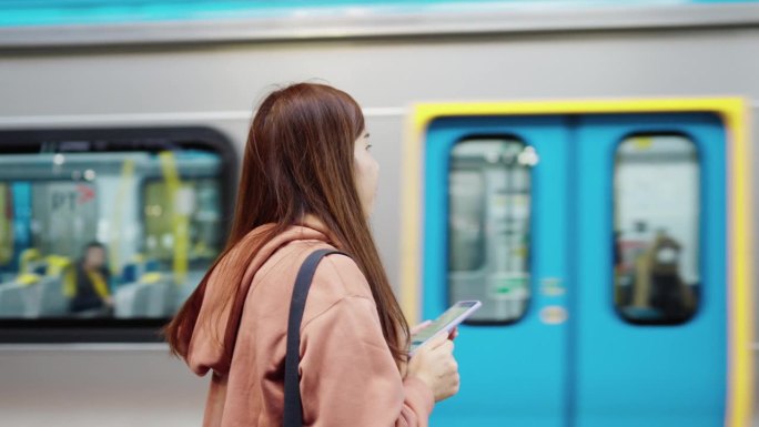 背着双肩包的女子在高速列车旁等地铁