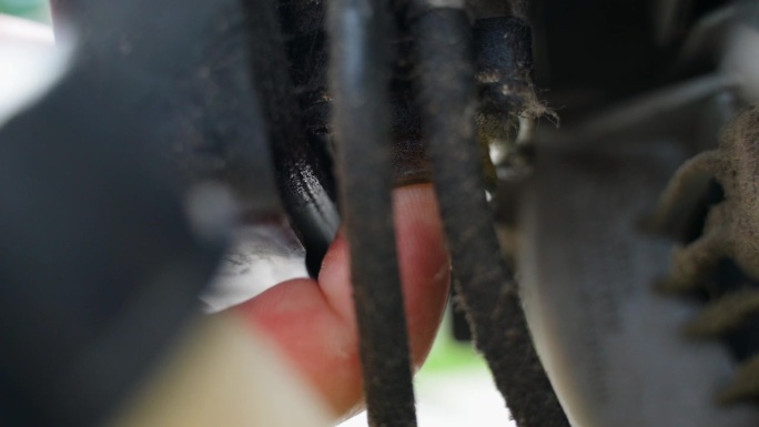 一个手指将燃料注入汽油修剪器的化油器(特写)。准备启动割草机发动机，将汽油-机油混合物填满橡胶内胆