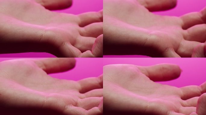 手部皮肤在粉色霓虹灯下，女性人体部位和紫外线、手臂表面微距拍摄。