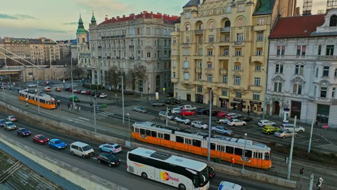 高角度无人机拍摄的有轨电车行驶在匈牙利布达佩斯历史建筑和多瑙河之间的道路上