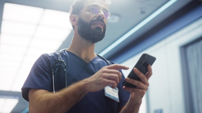 男护士值班时用智能手机查看短信和电子邮件。拉丁年轻诊所专业人员在现代医院走廊休息时刷社交媒体
