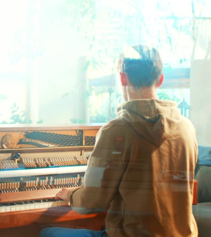 从窗户玻璃看到的后景，一名男学生正在练习钢琴课，在一架老式的开放式钢琴上演奏