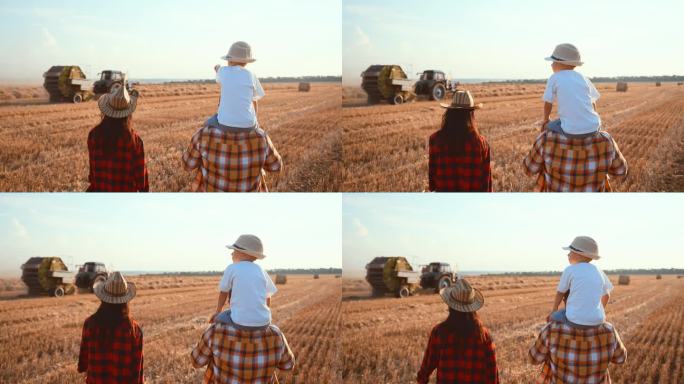 后视图一家人一起走在麦田里用稻草做的干草堆。男孩坐在他爸爸的肩膀上，伸出手臂。妈妈牵着孩子走。夏天的