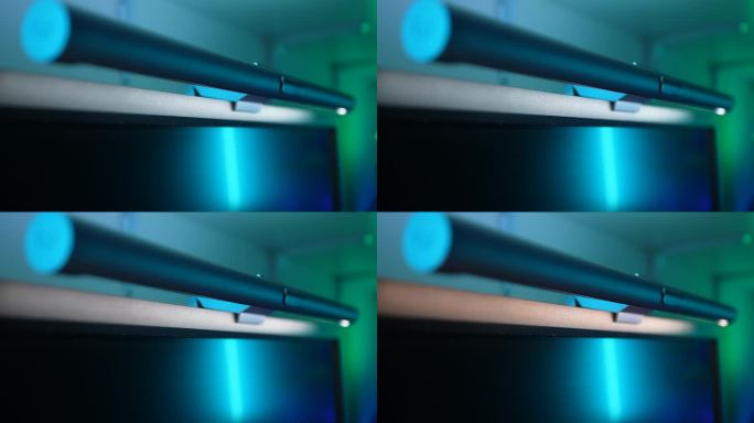 内饰现代化的暗室中，利用无线遥控器调节新型电脑显示器LED灯亮度的特写镜头。