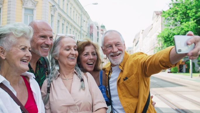 一群快乐的老年朋友在城市里散步，自拍。