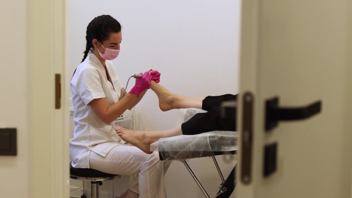 足疗专家，医学面膜制作足部足疗。在水疗沙龙接受古典五金足疗的女人的腿。腿部和指甲皮肤护理。水疗过程
