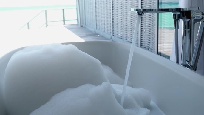 浴缸与泡沫和自来水在豪华酒店浴室。