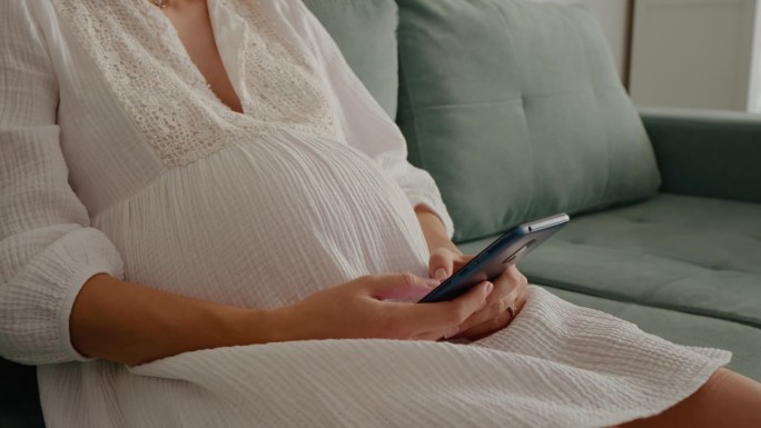未被认出的孕妇用智能手机玩游戏。