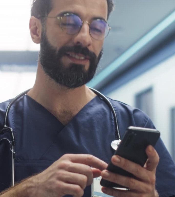垂直屏幕:男护士在值班时使用智能手机查看信息。拉丁年轻诊所专业人员在现代医院休息期间在社交媒体上滚动
