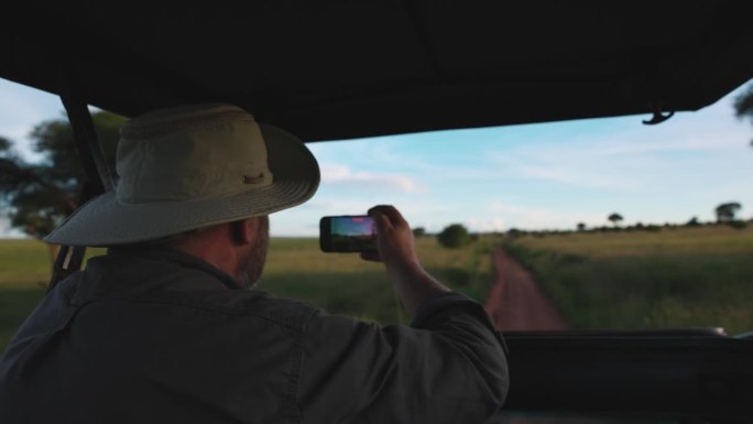 游客在塔兰吉雷的移动车辆上拍摄。一位男游客从行驶的车辆上拍摄野生动物的魔力