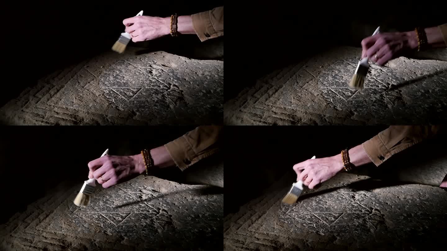 一位男性考古学家正在用刷子擦拭一块石板上的灰尘，石板上刻着犹太六角大卫之星的古老标志。历史发现证实了