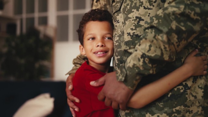 可爱的小男孩拥抱穿着军装的父母，迎接父亲的归来