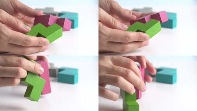 女性手持一块木块拼图。木材立方体堆叠。决策过程的概念，创造性，逻辑思维，聪明的游戏。手工折叠彩色木块