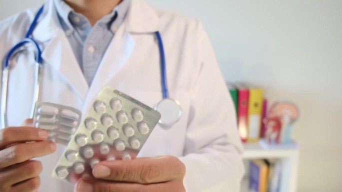 一名医生手里拿着药片和药盒。医疗、健康和疾病的概念。