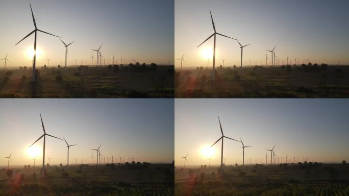日出时背光风力涡轮机的航拍照片。
