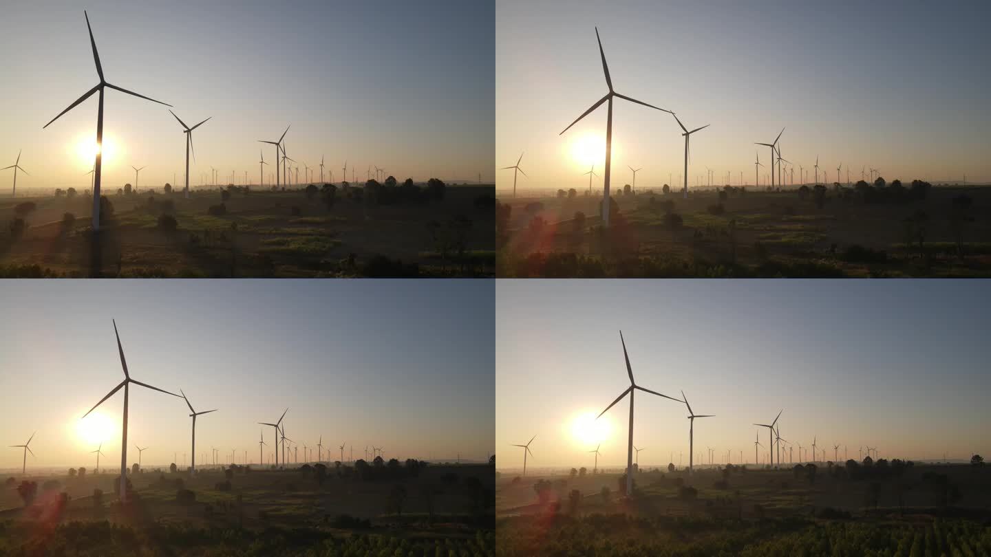 日出时背光风力涡轮机的航拍照片。