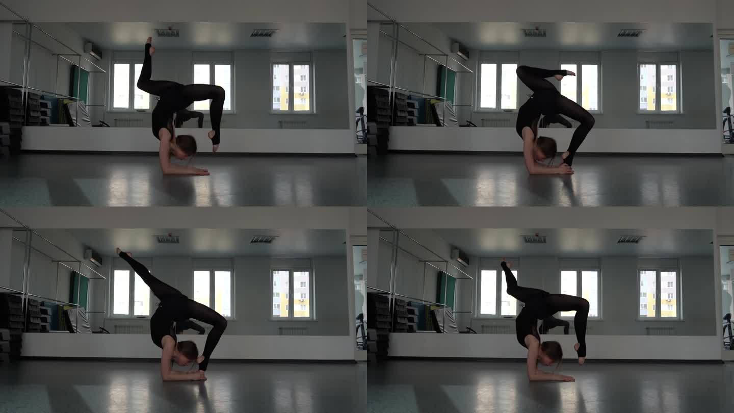 体操女运动员将腿向后拉至头部，在瑜伽房里做伸展运动