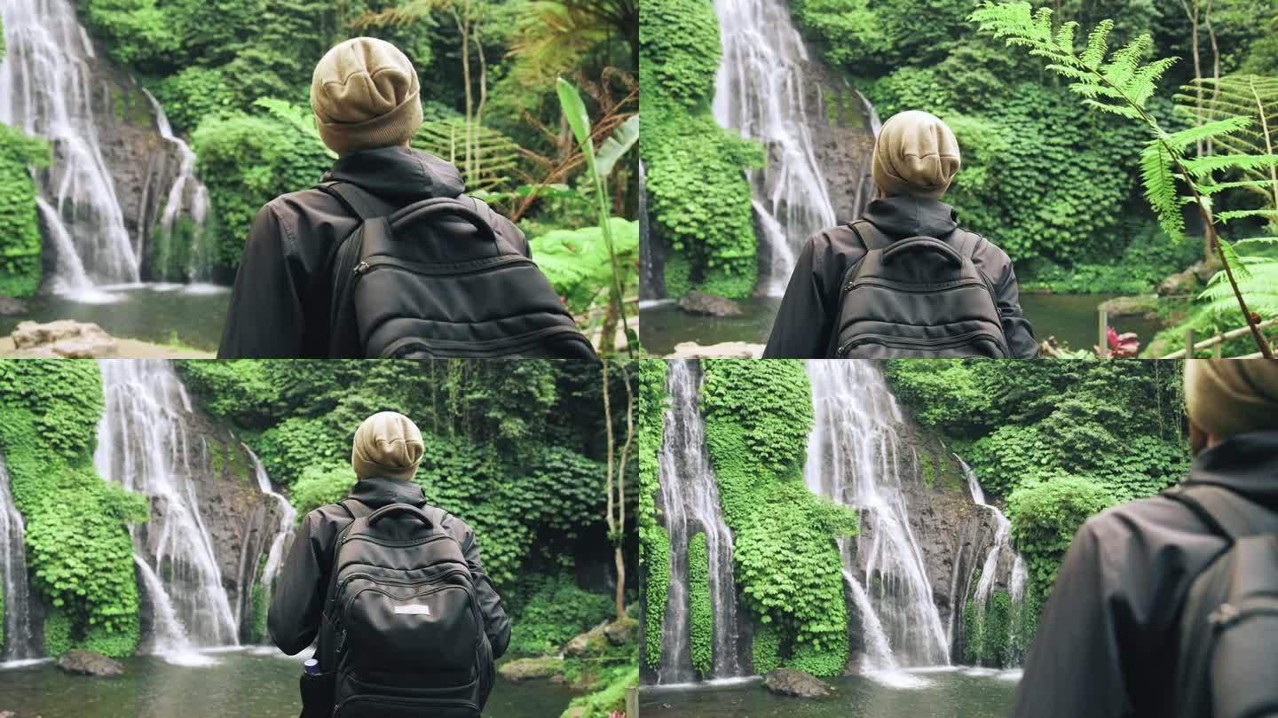 成年男子在绿色大自然中旅行到森林瀑布。一个不知名的年轻人走到丛林瀑布的旅行目的地。《天堂岛之旅》中个