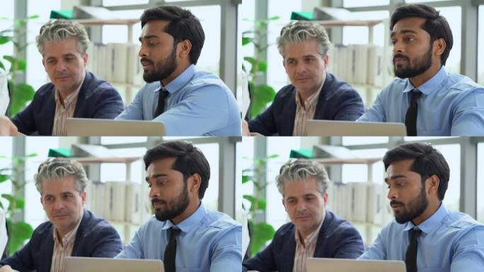 年轻的印度商业经理在办公室里与同事在桌子上讨论或辩论数据。愤怒的领导会站在同事身后解释和回答问题
