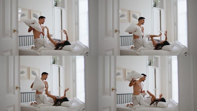 性感男人在舒适的公寓里玩枕头。快乐的夫妻一起打靠垫