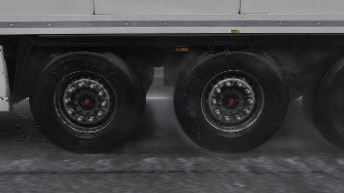 特写卡车车轮轮胎通过非常多雨的高速公路