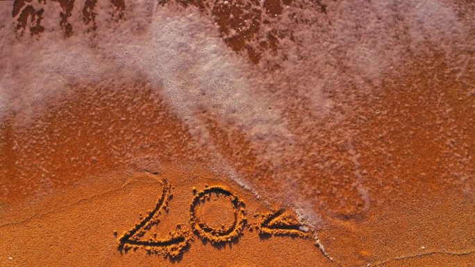 告别旧的2023年，迎接新的2024年，文字写在海岸边的海沙和浪花上
