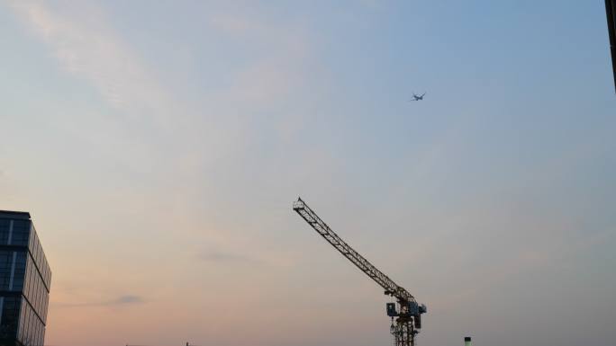 飞机飞过大楼 夕阳下塔吊