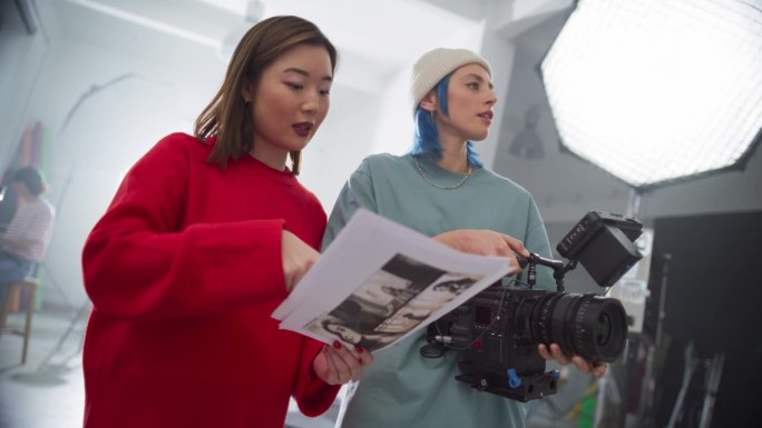年轻女导演在光明工作室指导专业电影摄影师拍摄视频。专业的工作人员作为一个团队在相机上捕捉美学镜头