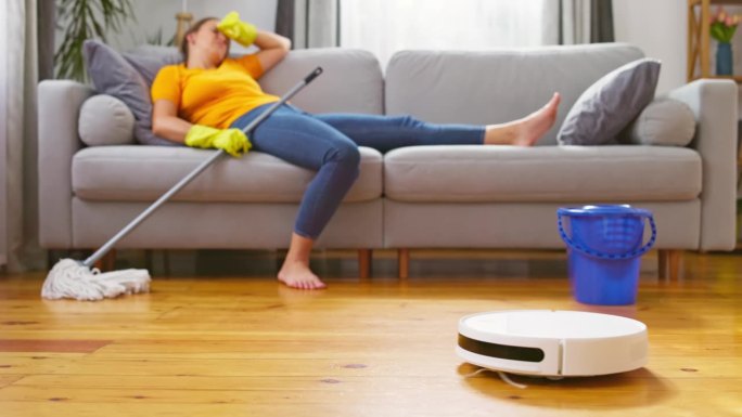 厌倦了没完没了的清洁，一位女士躺在舒适的沙发上，让机器人吸尘器来打扫。创新的清洁技术